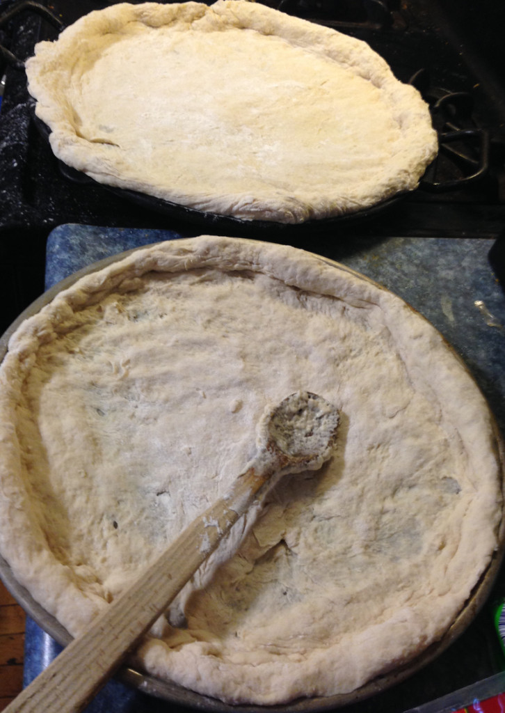Working the pizza crust into the pans. I especially love the Lodge Cast Iron pans and need to buy more of them. I always end up with one big pizza and one super puffy smaller one! Lopsided pizza goodness!